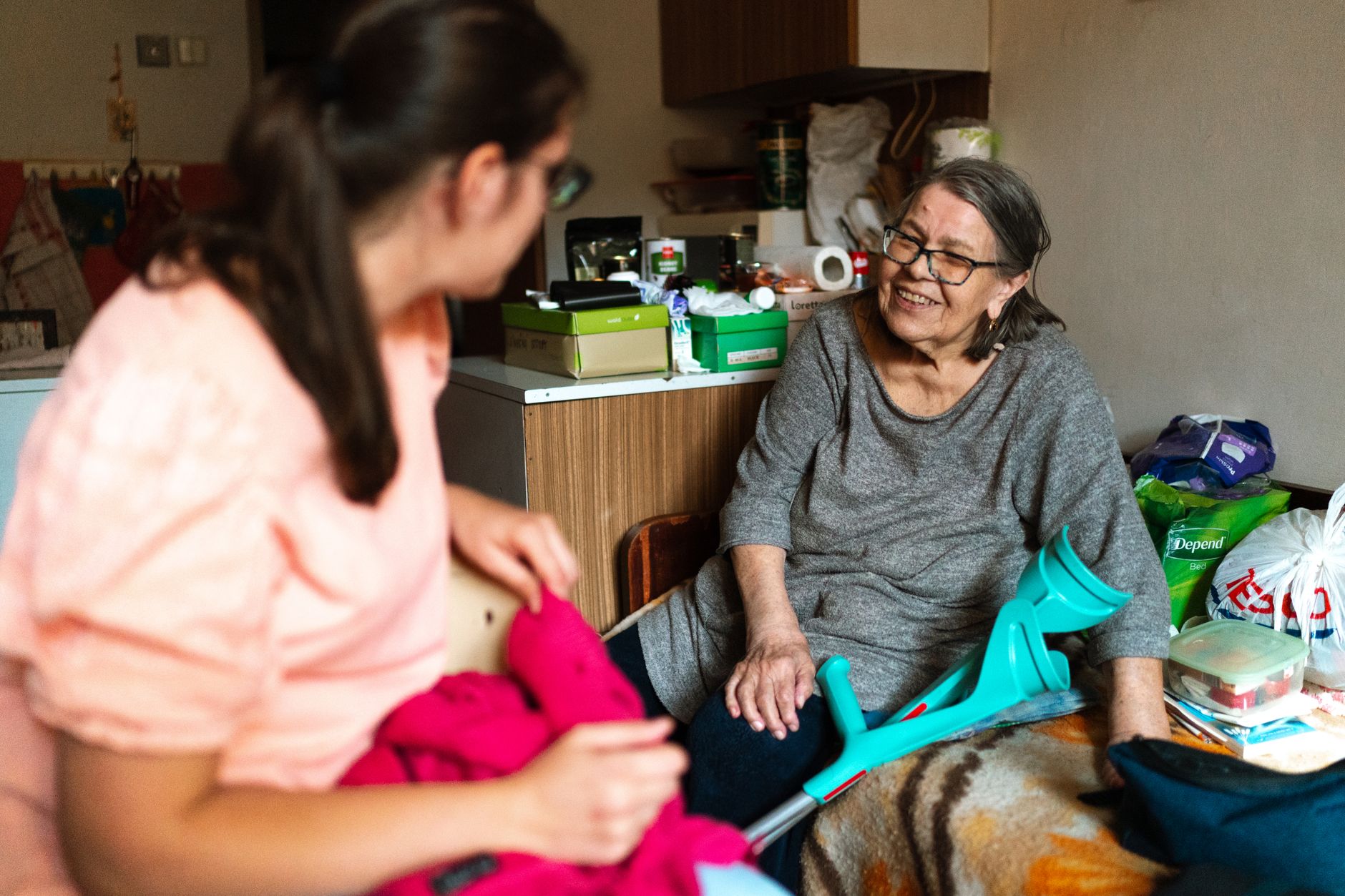 An older woman and a carer having coffee at a kitchen table